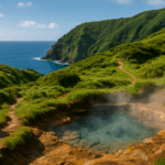 Weites, natürliches Landschaftsfoto der Azoren, sanfte grüne Hügel und steile Klippen am Meer, im Vordergrund eine dampfende heiße Quelle mit glasklarem Wasser, im Hintergrund ein Wanderpfad mit wildem, unberührtem Terrain, darunter sanftes, blaues Atlantikwasser.