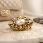 Vintage Goldbrosche mit Perle auf Marmorfläche – Retro Schmucktrend 2026 als modernes Statussymbol